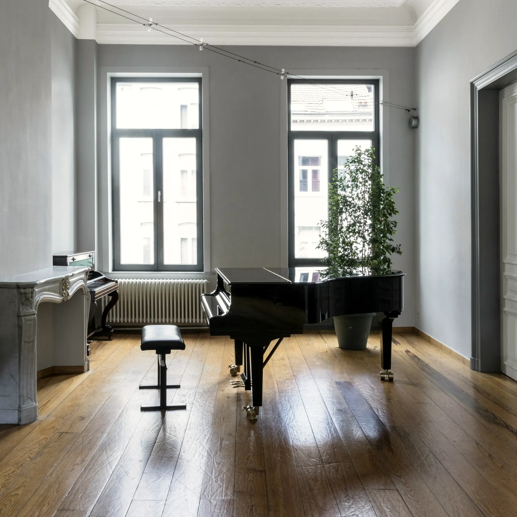 Piano à queue dans une pièce lumineuse aux hauts plafonds
